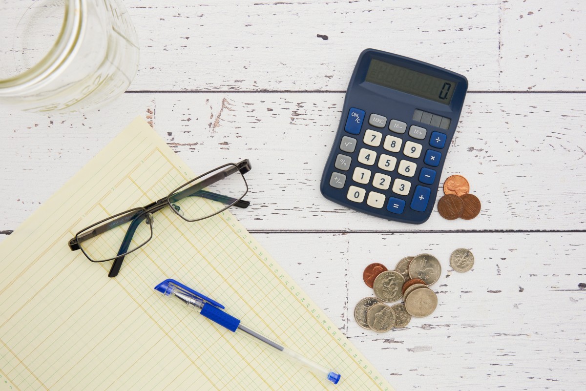 Coins, a calculator and a notebook arranged for budget tracking.