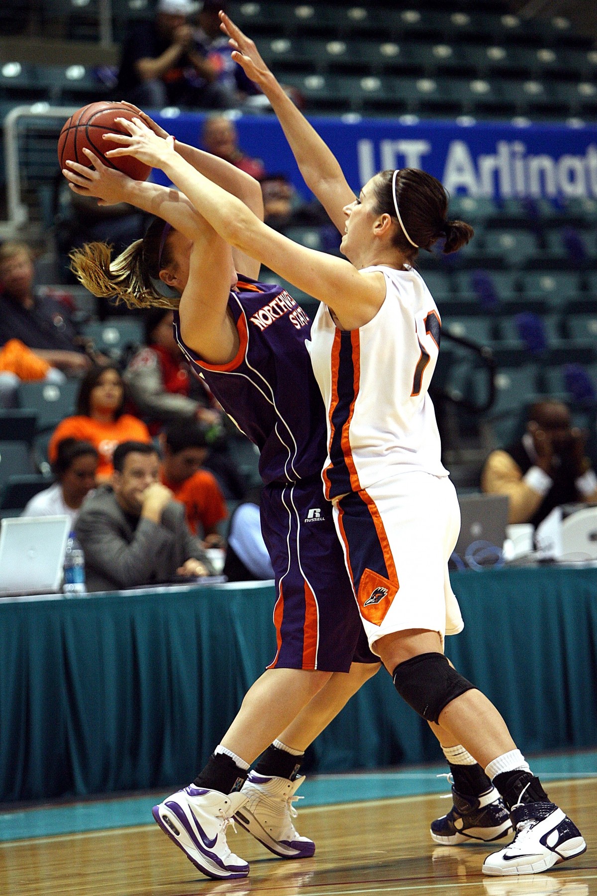 A basketball player drives toward the hoop as a defender contests the play.