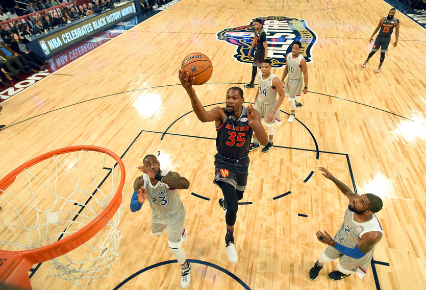 An NBA player drives toward the basket during a basketball game.