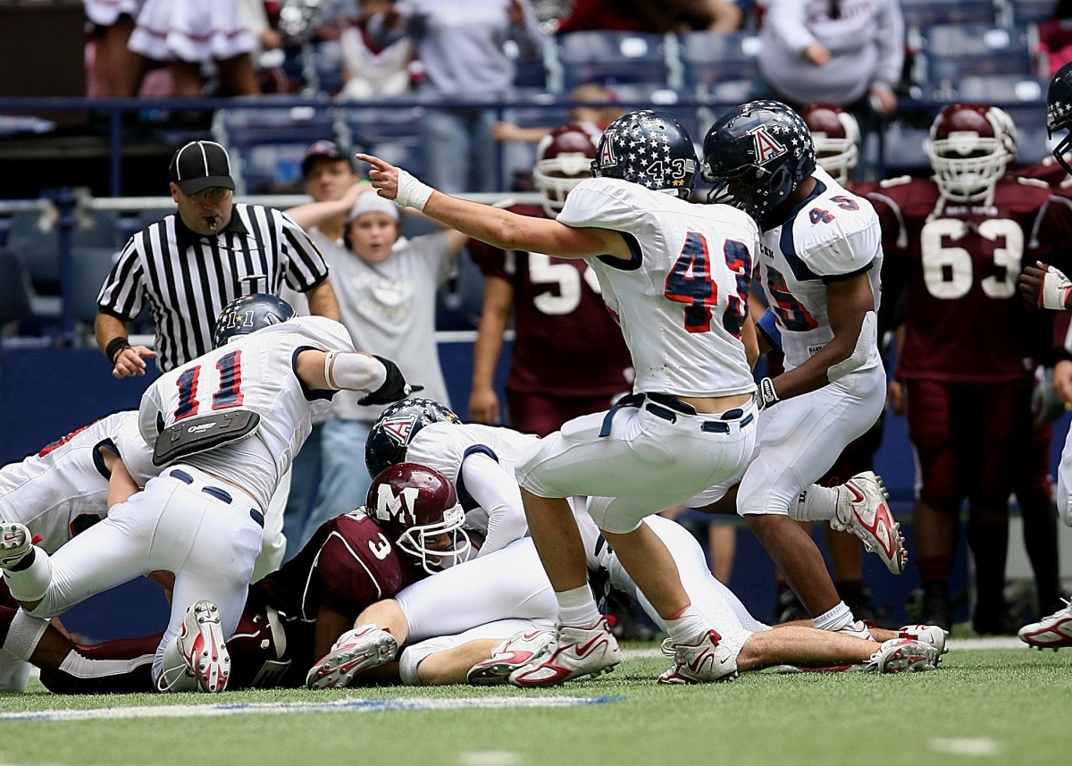 An American football player reaches for a loose ball during a play.
