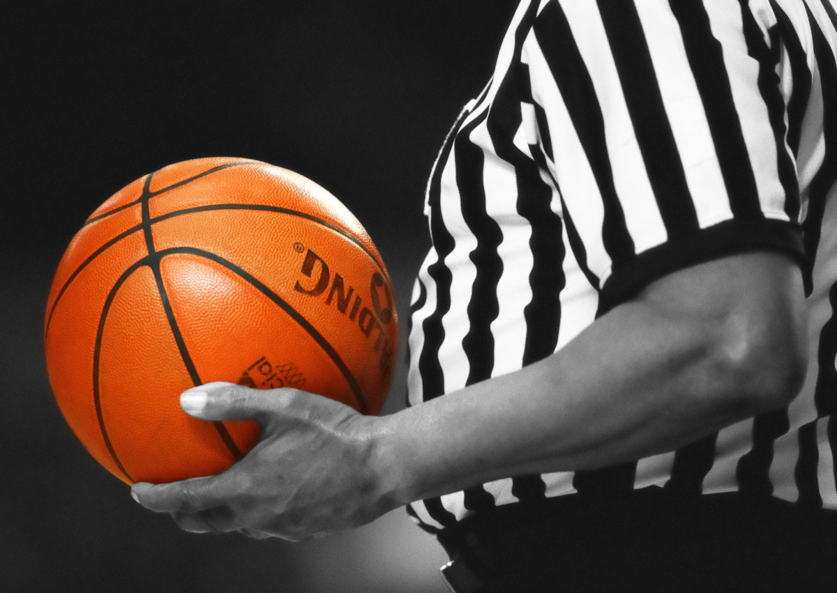 A basketball referee holds the ball between plays.