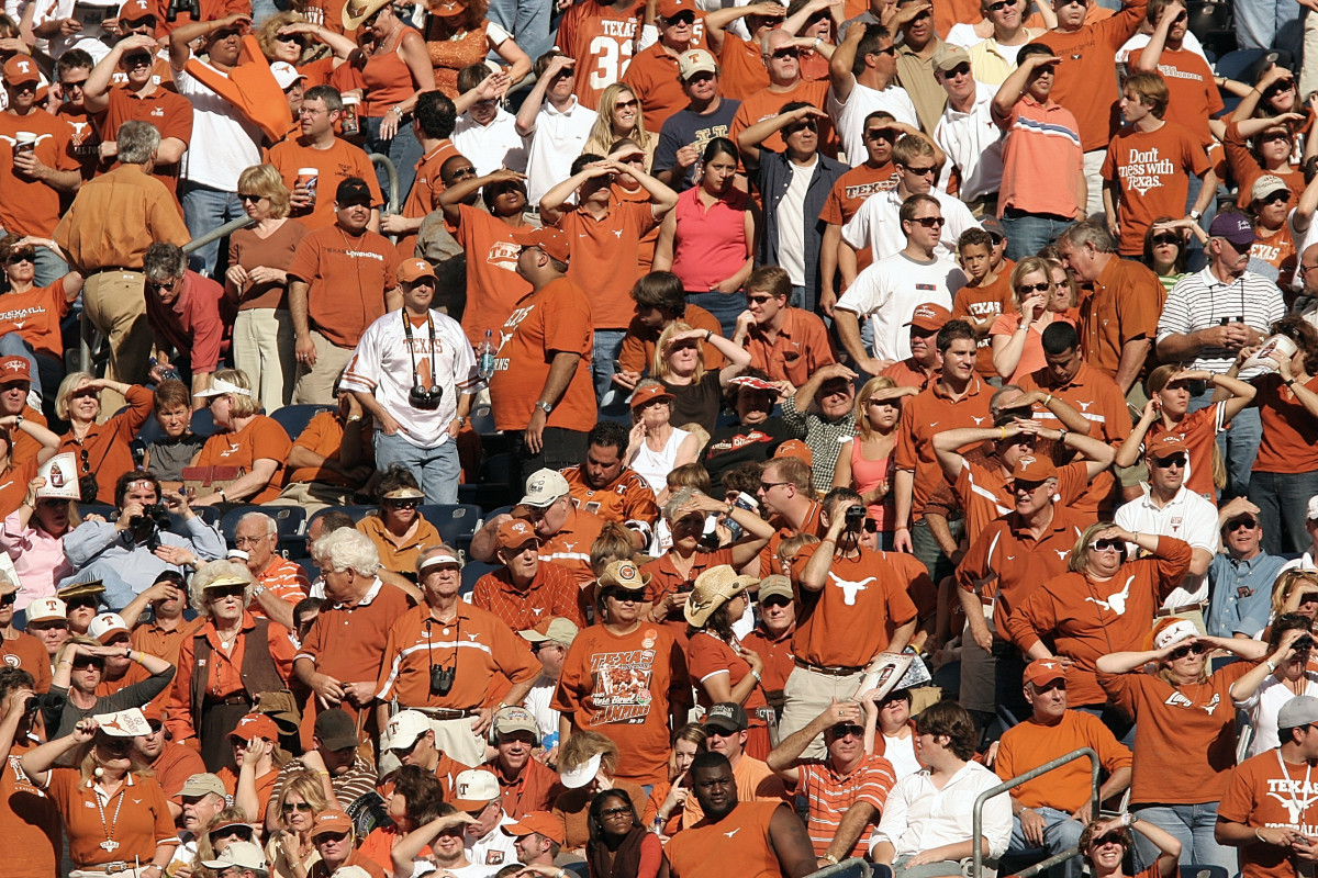 Fans follow an American football game from the stadium stands.